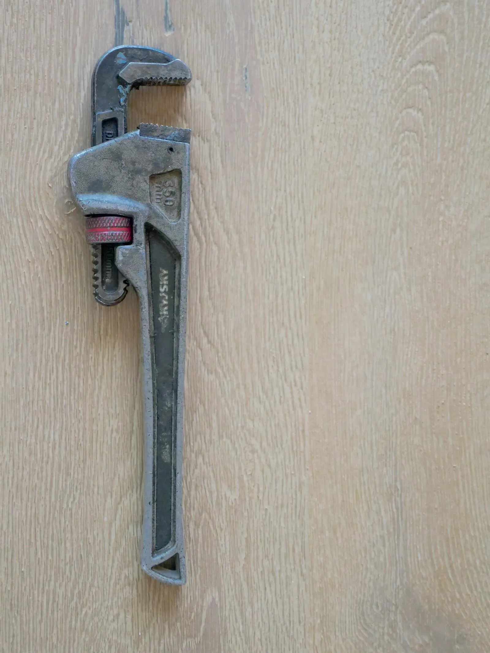 A pipe wrench resting on an oak floor