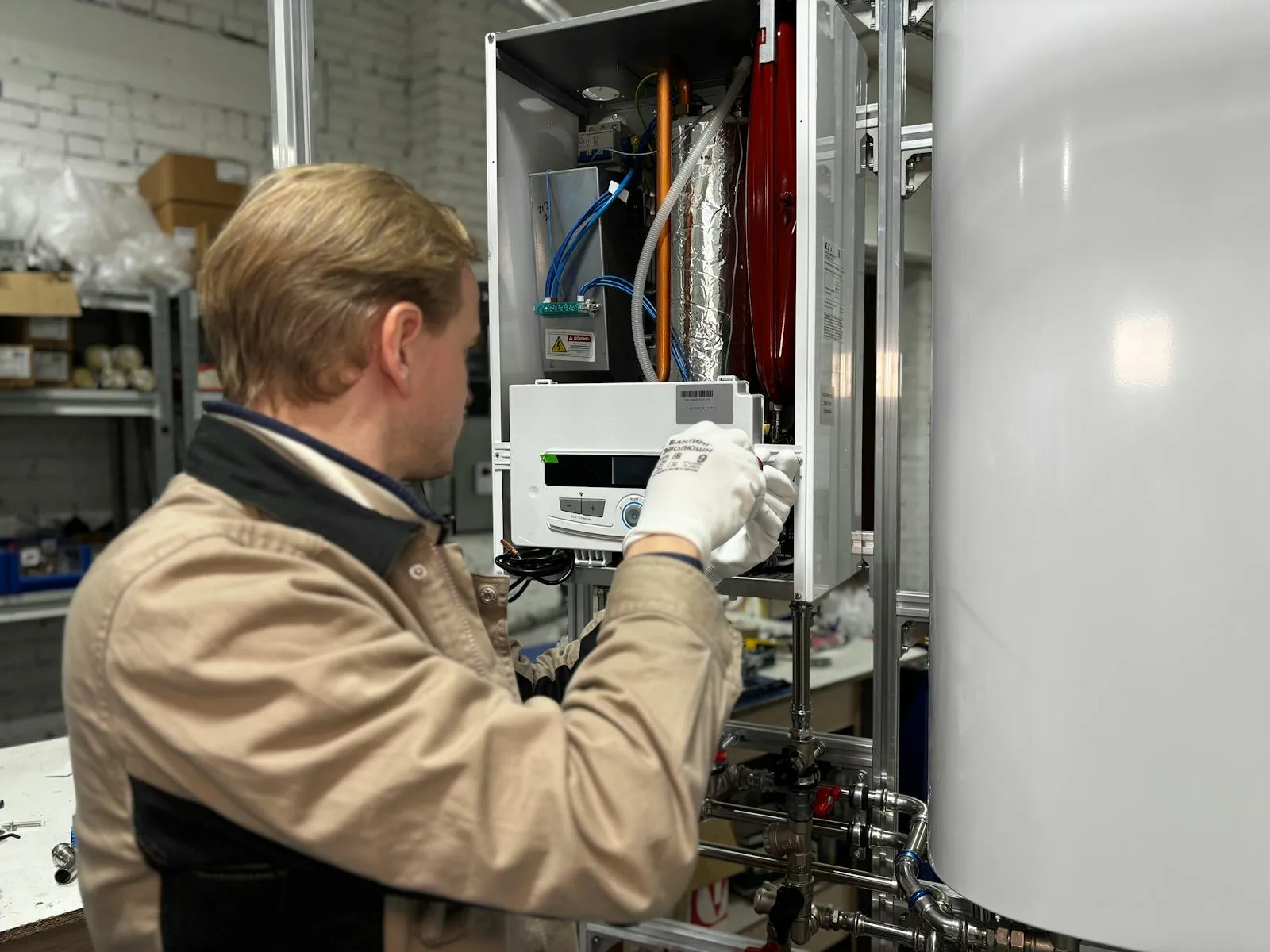 Engineer servicing a wall-hung boiler in a utility room