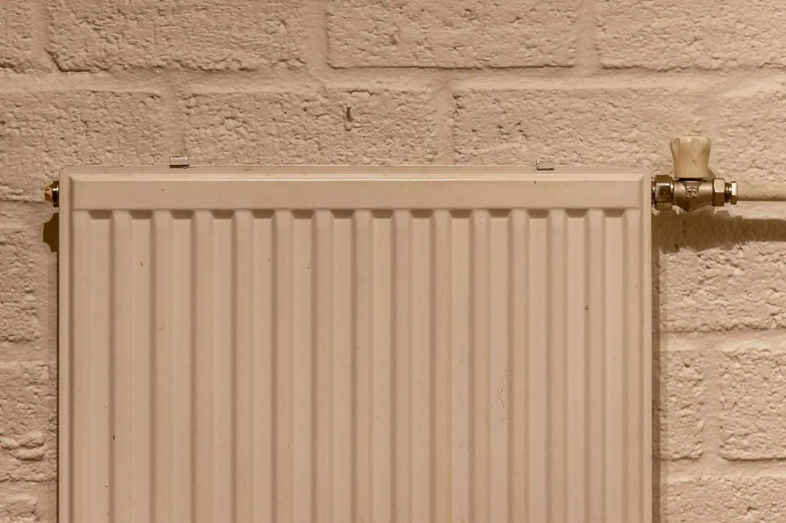 A clean white wall-mounted panel radiator with a chrome valve